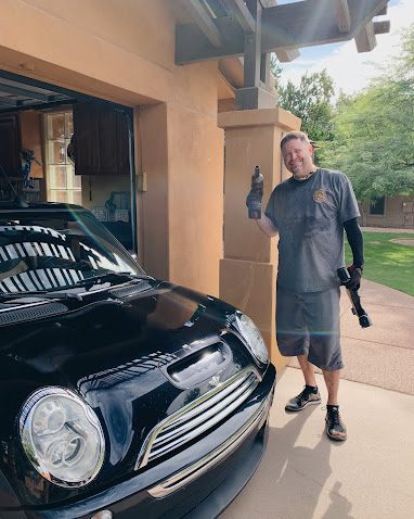 Nate Hauger giving a thumbs up next to a MINI Cooper after a driveway brake job